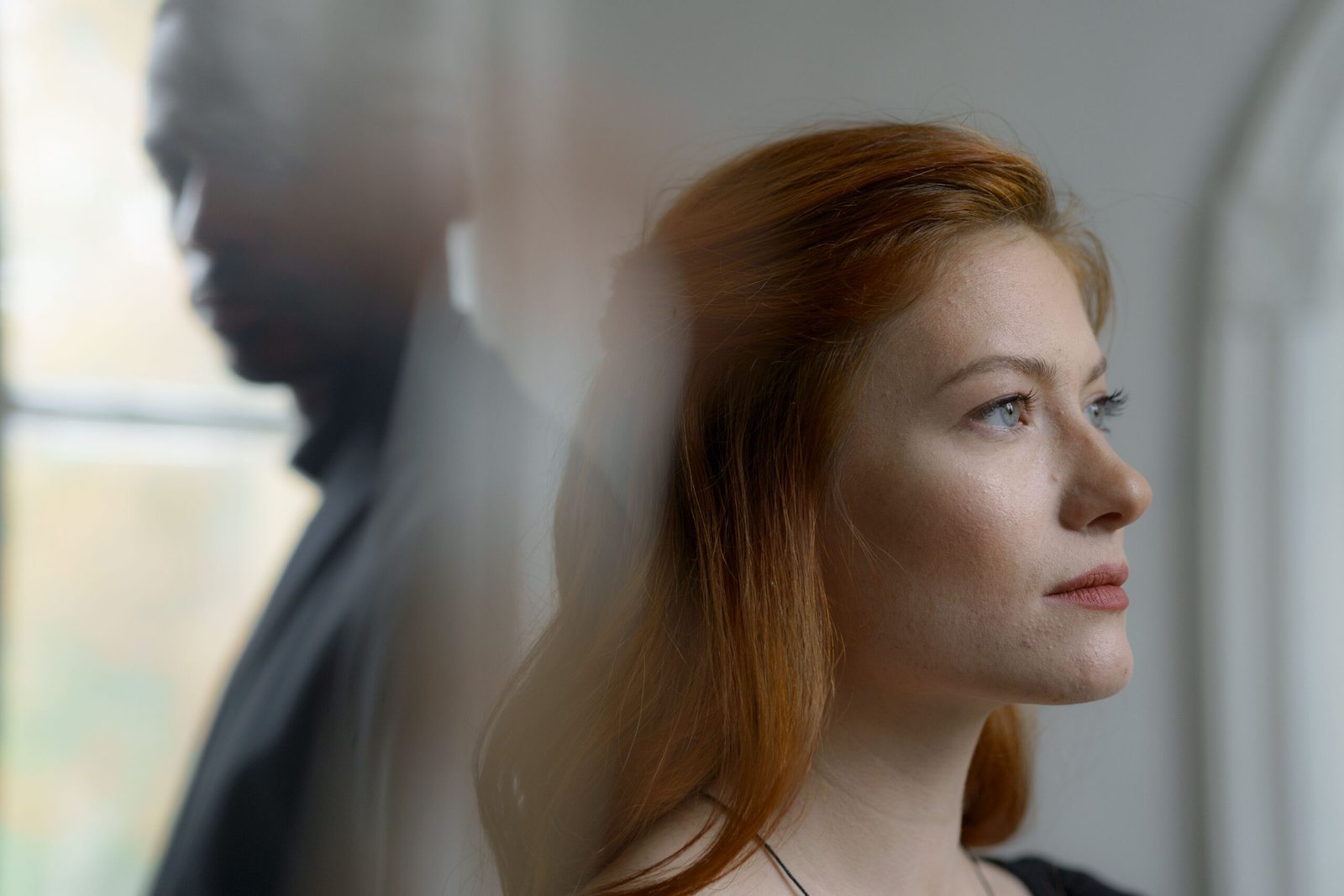 Woman looking away while sitting beside an emotionally distant partner.